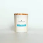 A scented candle served in white glass, wooden cover with label Blue Hour 140g made by ccccandleco